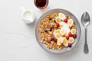 Healthy breakfast. Fresh granola, muesli with yogurt banana and cranberry on light gray background....