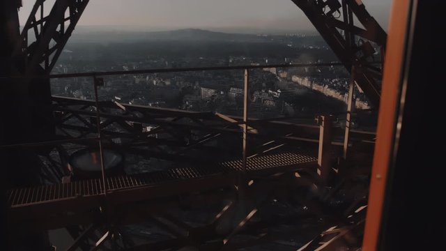 Cinematic background view from inside glass elevator moving upwards to Paris Eiffel Tower top among steel structure bars