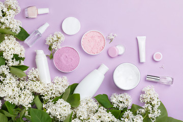 Fototapeta na wymiar Natural woman make up cosmetics with spring white lilac bloom. Top view. Spring female decorative cosmetics on purple background. Natural organic cosmetic for make up. Cosmetic and brushes in blossom