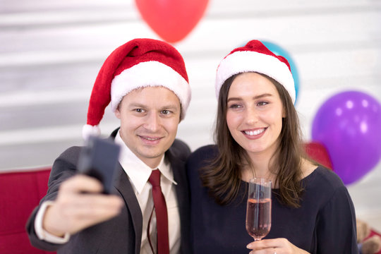Lovers wear a red Santa hat, holding a phone to take pictures together New year festival