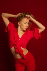 Dynamic shot of a young beautiful sexy woman in a red dress dancing on a red background