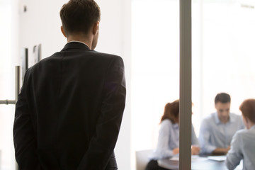Rear view nervous man standing near door waiting job interview