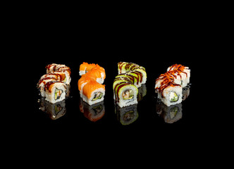 sushi and rolls with different fillings on a black background with reflection