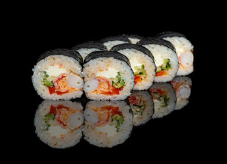 sushi and rolls with different fillings on a black background with reflection