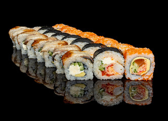 sushi and rolls with different fillings on a black background with reflection