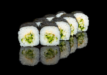 sushi and rolls with different fillings on a black background with reflection