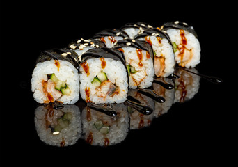 sushi and rolls with different fillings on a black background with reflection