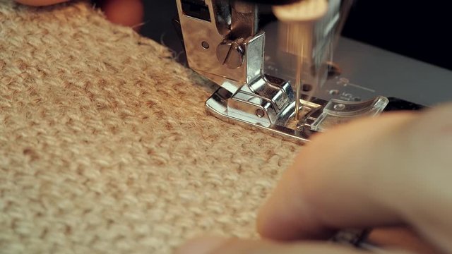 seamstress sewing on jute fabric on a sewing machine