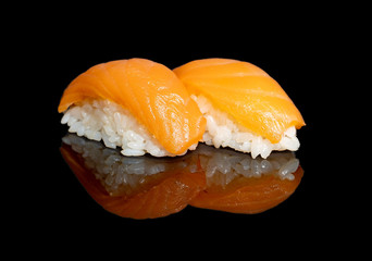 sushi and rolls with different fillings on a black background with reflection