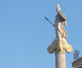 Athena and small sphinx statue under blue sky background, space for text