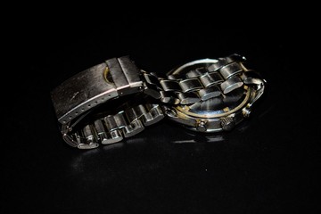 Metal wrist watch on black ground