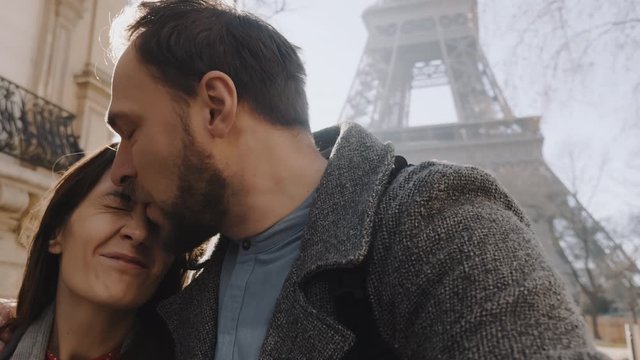 Close-up happy couple walk together hugging and kissing near Paris Eiffel Tower. Dating and family concept slow motion.