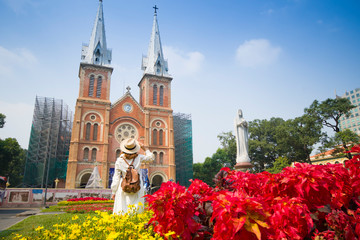 Woman tourist is sightseeing in front of Notre Dame Cathedral of Saigon in Hochiminh City in Vietnam. - obrazy, fototapety, plakaty