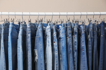 Fototapeta premium Rack with stylish jeans on beige background, closeup