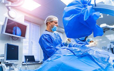 Process of trauma surgery operation. Group of surgeons in operating room with surgery equipment....