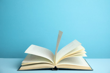 Open old hardcover book on light blue background