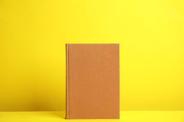 Hardcover book on yellow background. Space for design