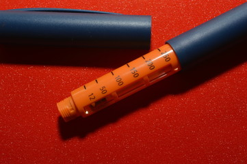 on a red background, a syringe pen for the introduction of insulin to a patient with diabetes, endocrinological diseases