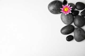 Fototapeta na wymiar Stones with lotus flower and space for text on white background, flat lay. Zen lifestyle