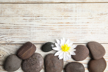 Stones with lotus flower and space for text on white wooden background, flat lay. Zen lifestyle