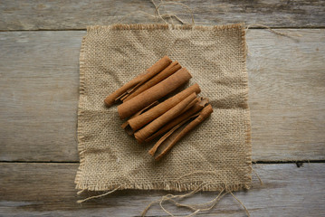 Cinnamon stick on rug sack on wooden background.