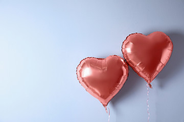 Heart shaped balloons near white wall. Space for text