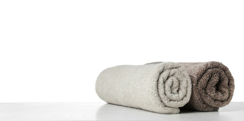 Fototapeta na wymiar Rolled fresh clean towels for bathroom on table against white background. Space for text
