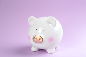 Cute white piggy bank on violet background