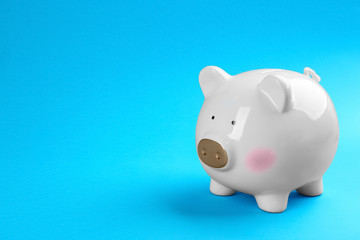White piggy bank on blue background. Space for text