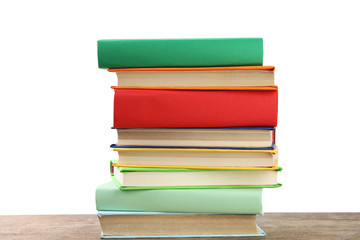Stack of colorful books on wooden table against white background