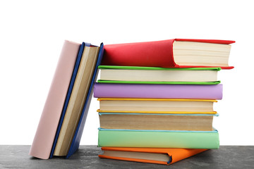 Stack of colorful books on grey stone table against white background