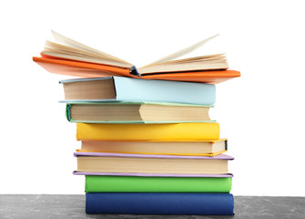 Stack of colorful books on grey stone table against white background