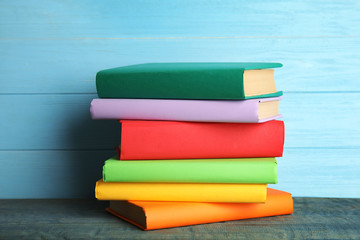 Stack of colorful books on light blue wooden table