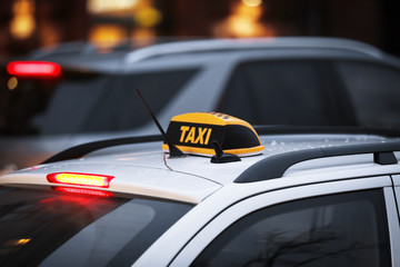 Taxi car with yellow checkered sign on city street in evening