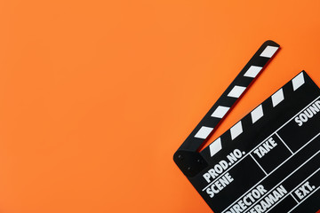 Clapper board on orange background, top view with space for text. Cinema production