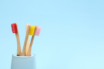 Toothbrushes made of bamboo in holder on light blue background. Space for text