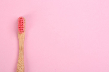 Toothbrush made of bamboo on pink background, top view. Space for text
