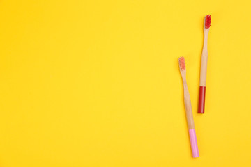Toothbrushes made of bamboo on yellow background, flat lay. Space for text