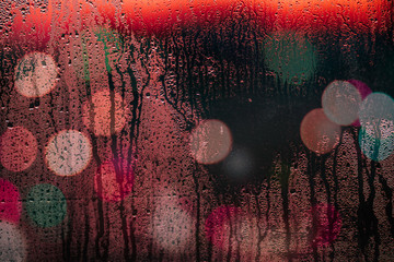 Rain drops on car window with light bokeh in night urban background.
