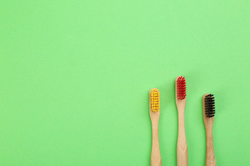 Natural toothbrushes made with bamboo on green background, flat lay. Space for text