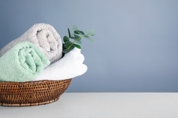 Fresh towels and eucalyptus branches on light wooden table, space for text © New Africa