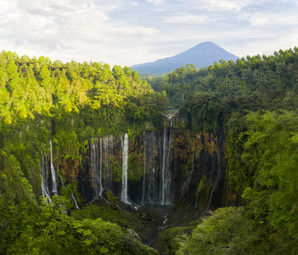 View from above, stunning aerial view of the Tumpak Sewu Waterfalls also known as Coban Sewu with the Semeru volcano in the distance, Malang Regency,East Java, Indonesia.