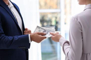 Man giving bribe money to woman indoors, closeup
