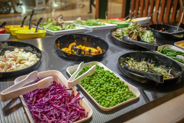 The salad buffet bar at the restaurant with lots of vegetables dishes.
