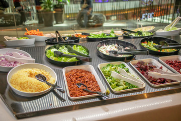 The salad buffet bar at the restaurant with lots of vegetables dishes.