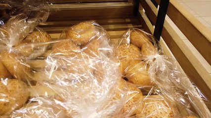 Supermarket bread department, breakfast rolls are lying on a wooden tray.