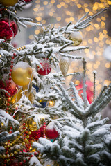 Big beautiful toys hang on a Christmas tree, hung with sparkling garlands and covered with snow. New Year decorations on the streets of Moscow. Winter New Year holidays. Selective focus