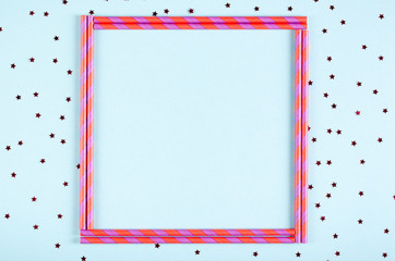 Pink frame from straw composition on blue background, party and celebration decoration.