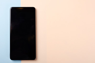 Black mobile phone composition on colored background. Flat lay.