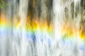 (Selective focus) Close-up view of the Tumpak Sewu Waterfalls with a beautiful rainbow formed by refraction of light in water droplets. Tumpak Sewu are waterfalls in East Java, Indonesia.